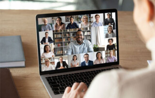 Image of a person on a laptop in a virtual meeting with many people