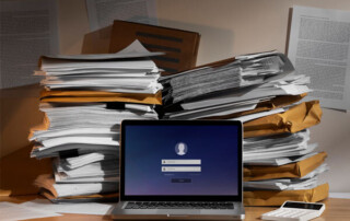Image of a laptop with many documents and a calculator on the desk